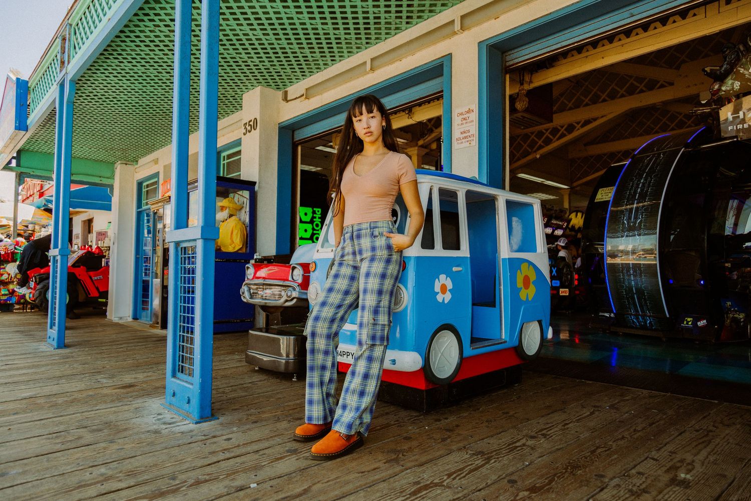 A person in plaid shorts stands in front of colorful blue and green storefronts at a shopping center.
