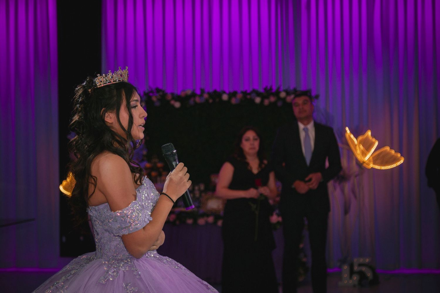 A couple dances together during their first dance at a wedding reception with purple lighting in the background.