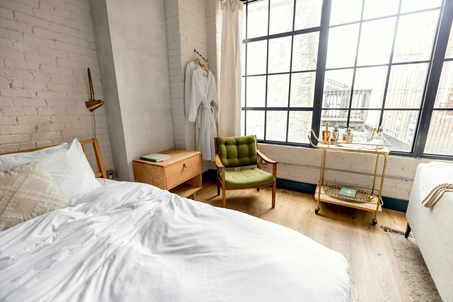 Bright modern loft apartment with exposed white brick walls, large windows, and contemporary furnishings.