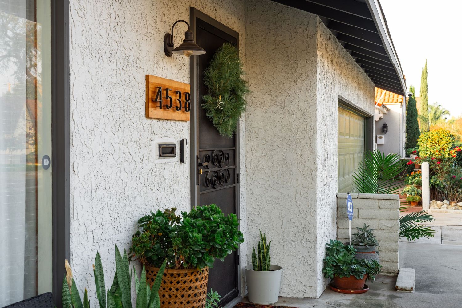A modern white stucco building exterior with covered walkway and potted plants along the entrance.