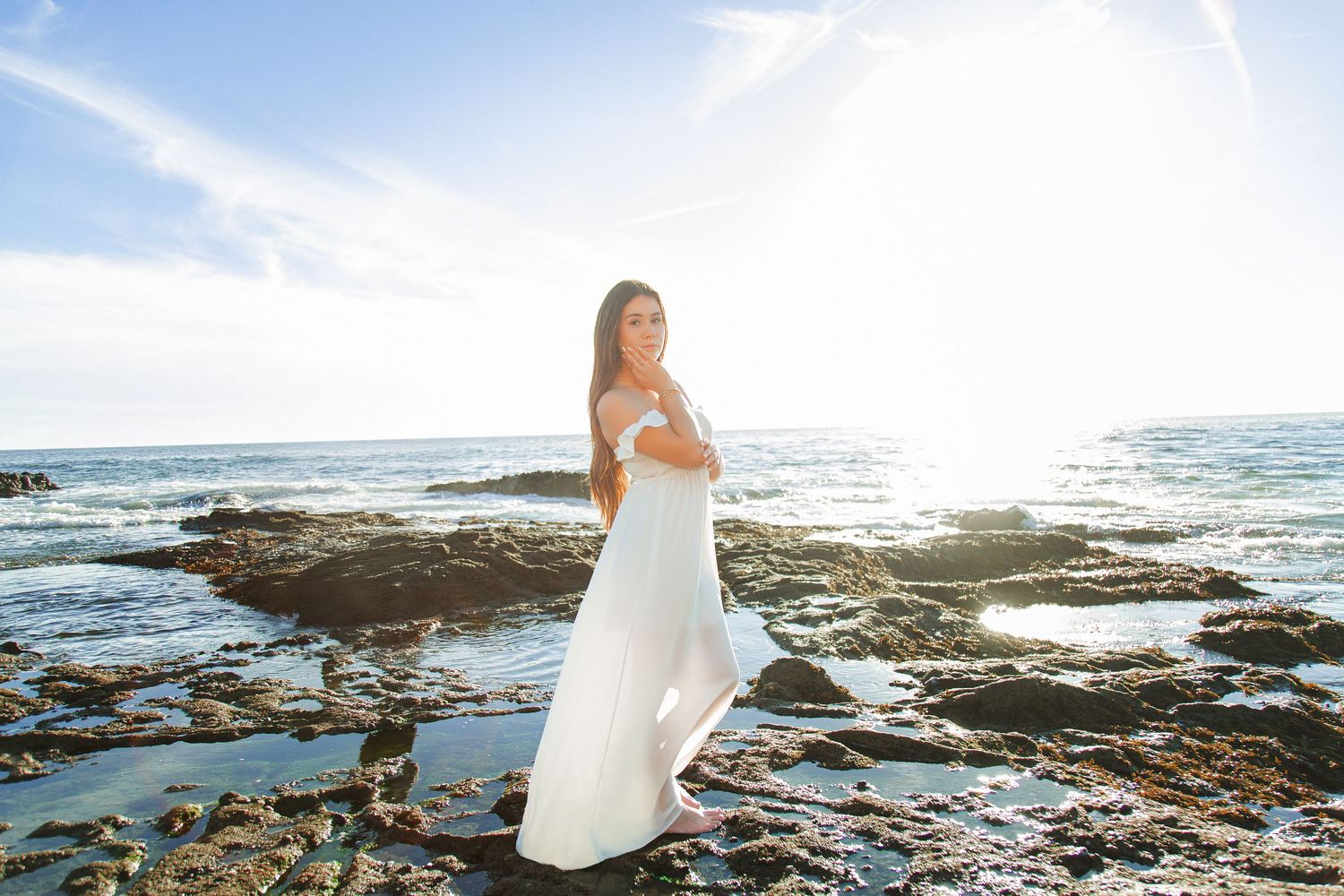 Scenic coastal wedding photography session with rocky shoreline and crashing waves at sunset.