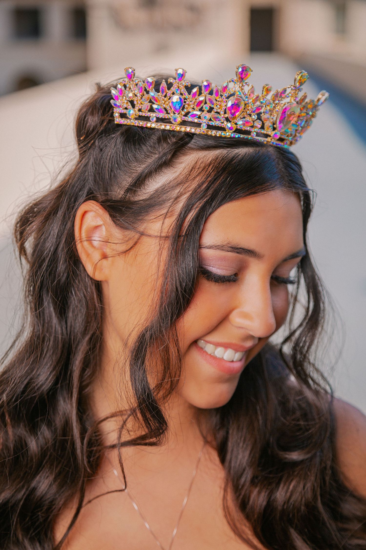 Close-up shots of a decorative pink and blue crown worn by a person with long dark wavy hair.