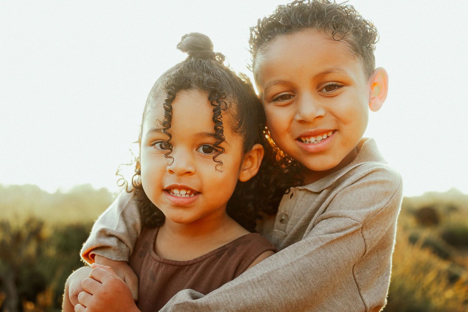 Children playing and laughing together outdoors during golden hour sunset.