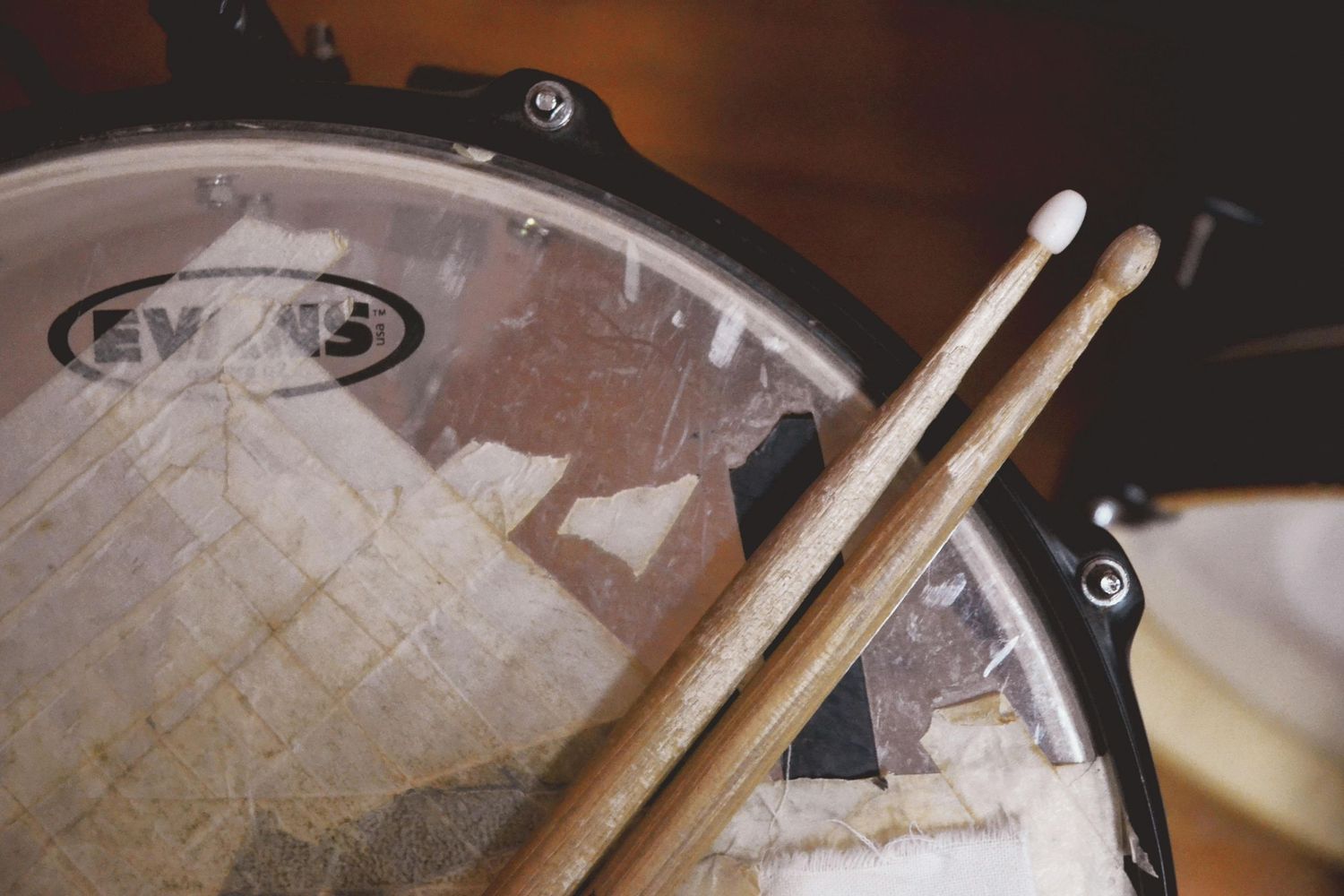 Close-up view of various drumsticks being used on a wooden drumming surface during a performance session.