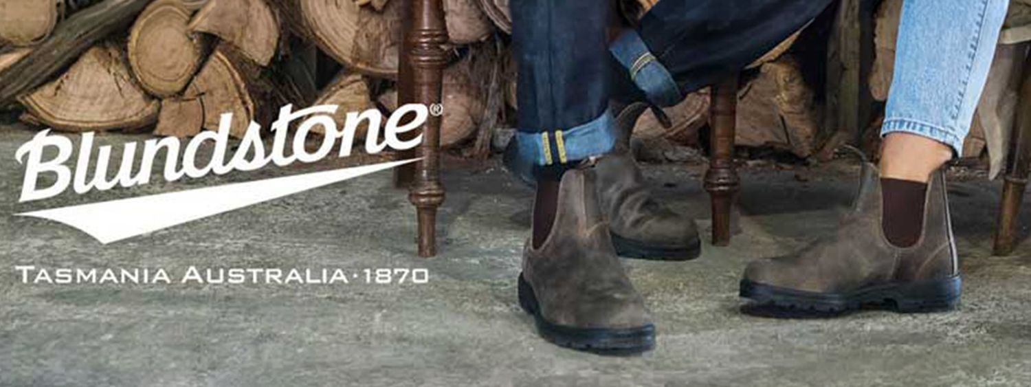 A close-up view of Blundstone branded boots and shoes displayed on a wooden surface.