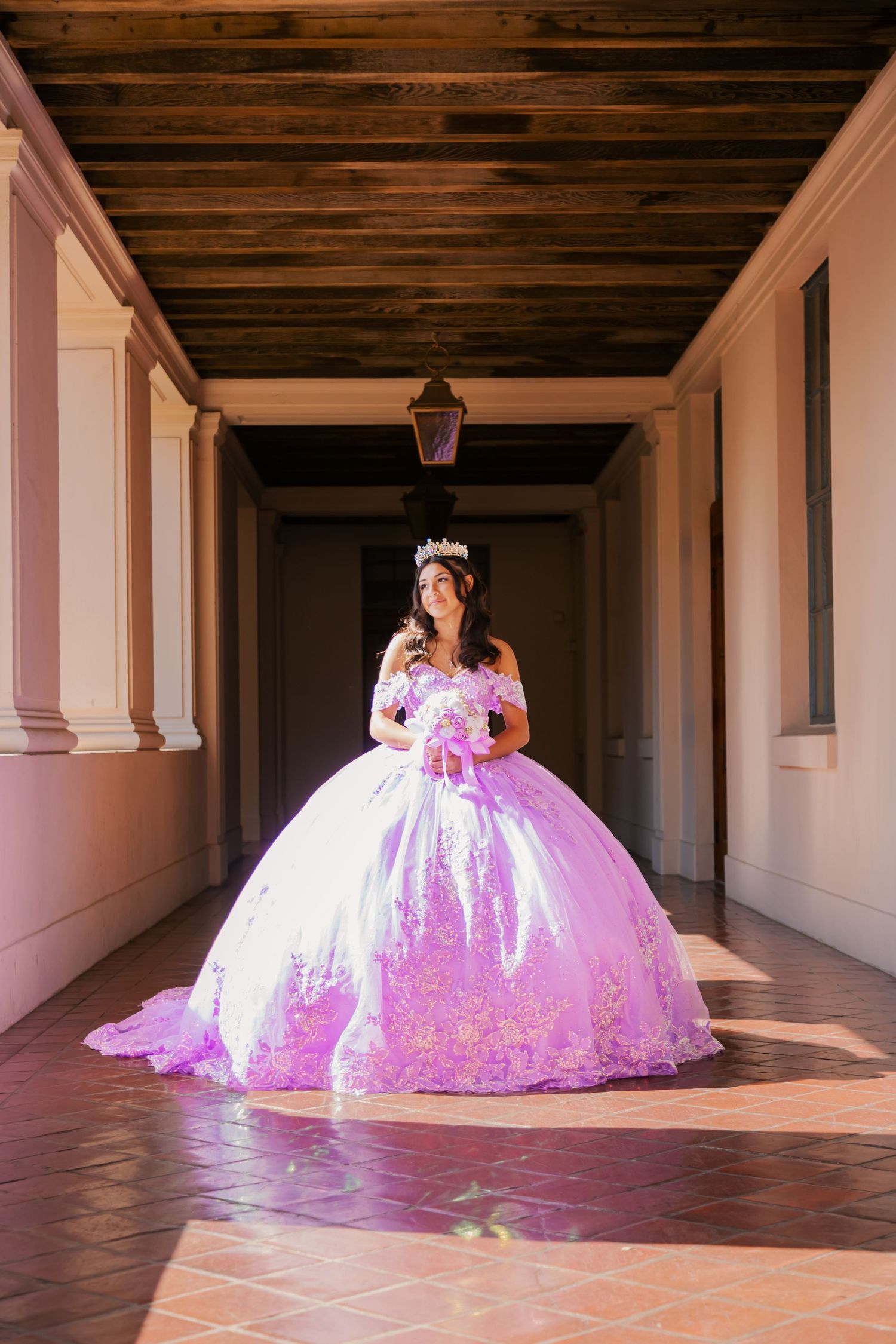 A quinceañera dress glows with pink LED lights in a series of photos taken along a historic colonnade hallway.