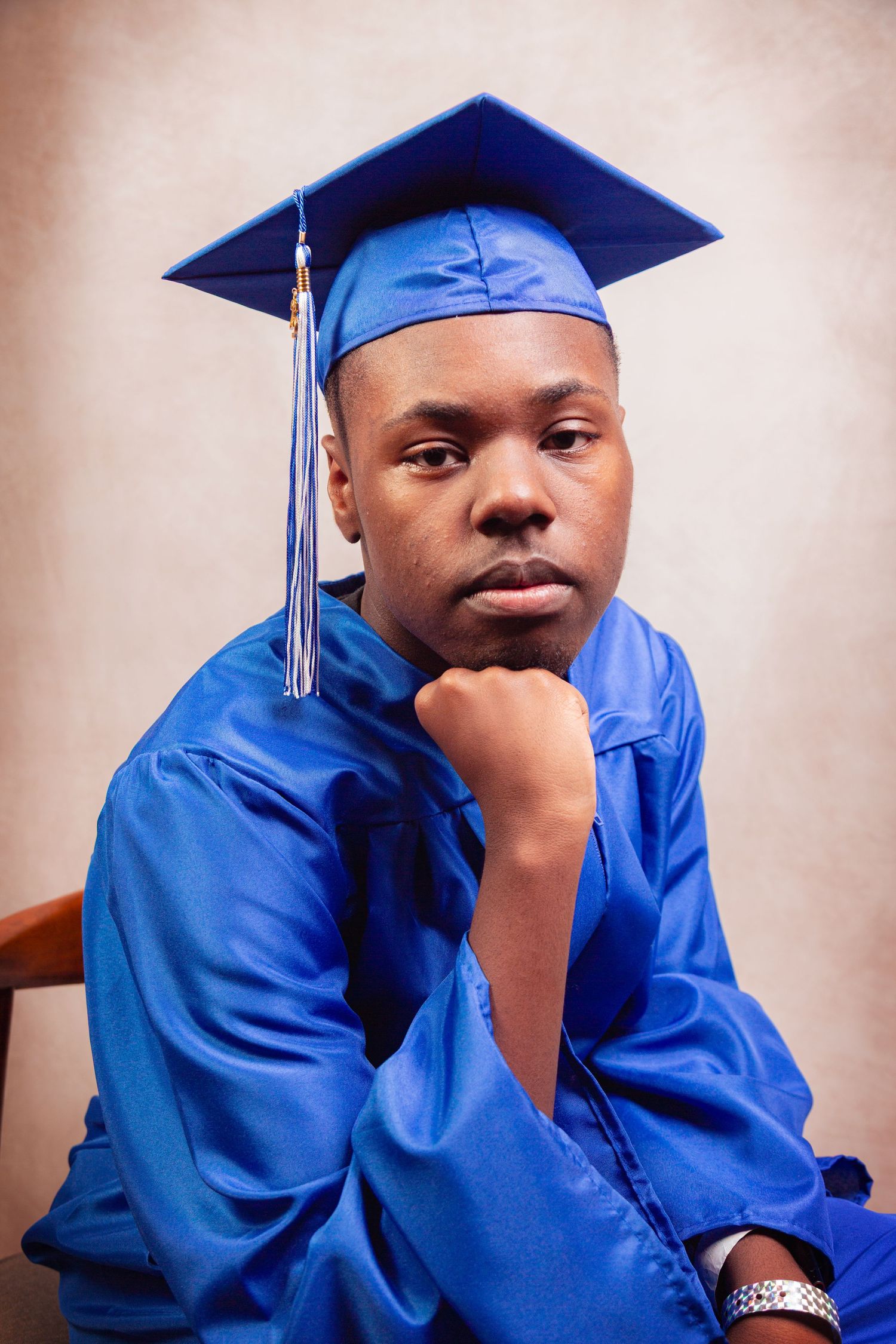 Graduate in bright blue cap and gown poses thoughtfully in a series of graduation portraits.