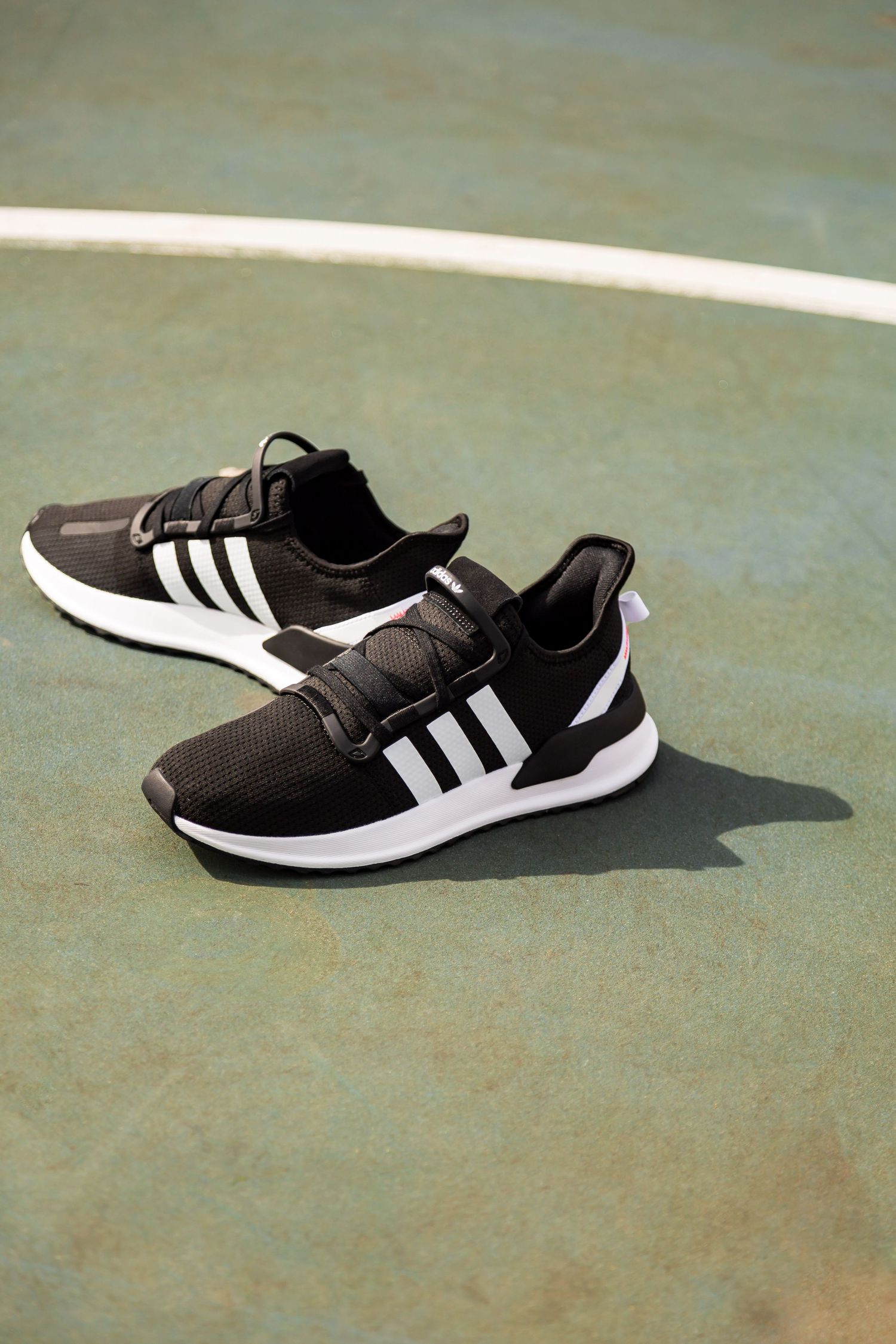 Black and white athletic sneakers shown from different angles on a textured green surface.