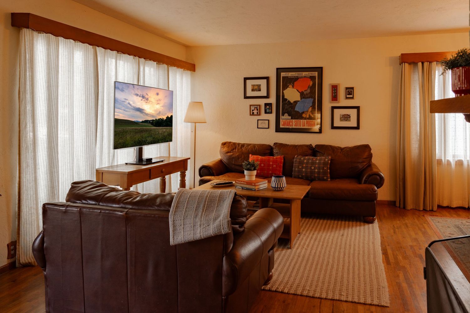 Panoramic view of a modern living room interior with brown leather furniture and warm lighting.