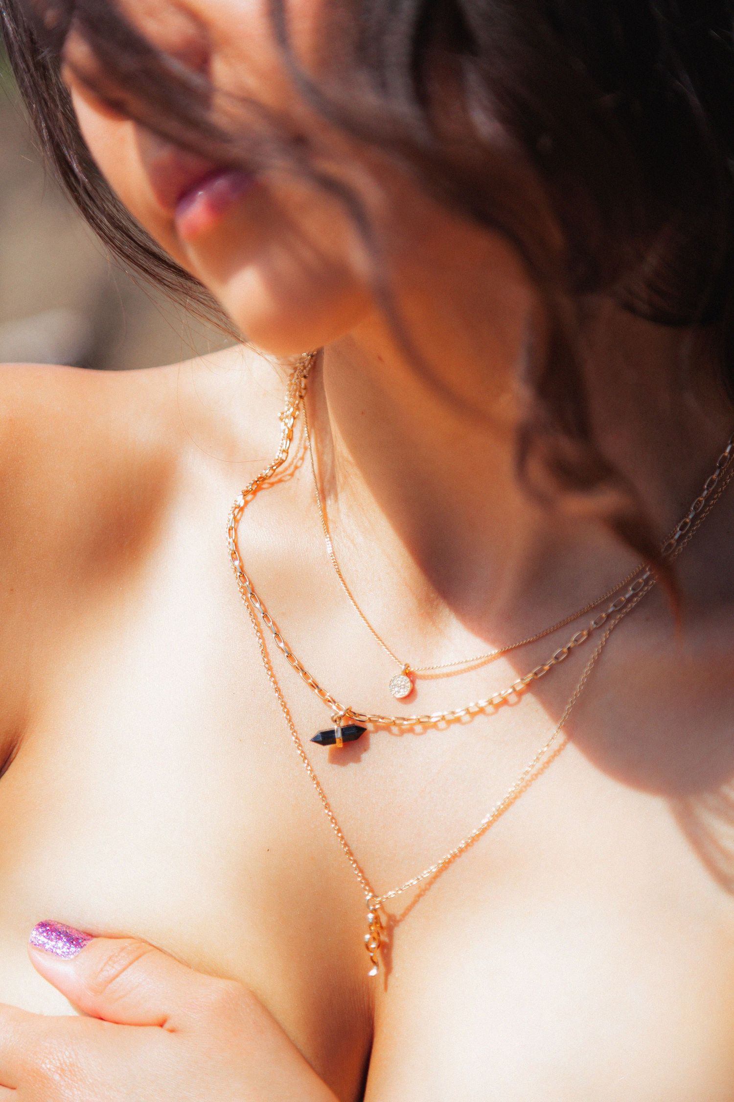 Close-up view of delicate rose gold chain necklaces layered against soft skin in natural lighting.