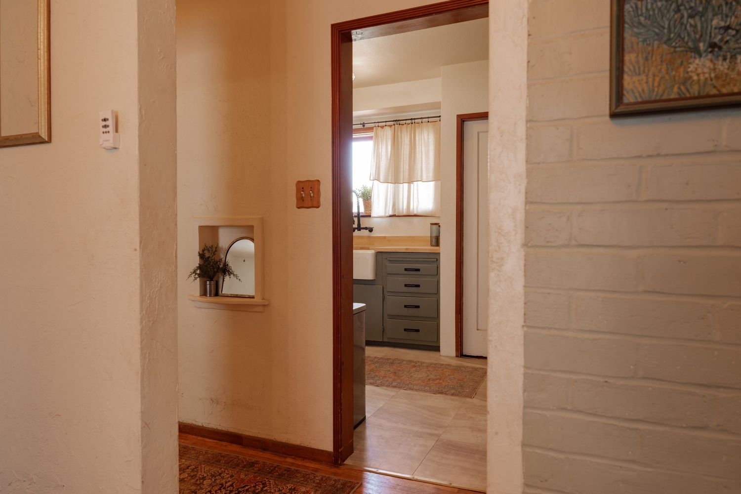 Interior hallway with white painted brick walls and hardwood flooring leading to multiple doorways.