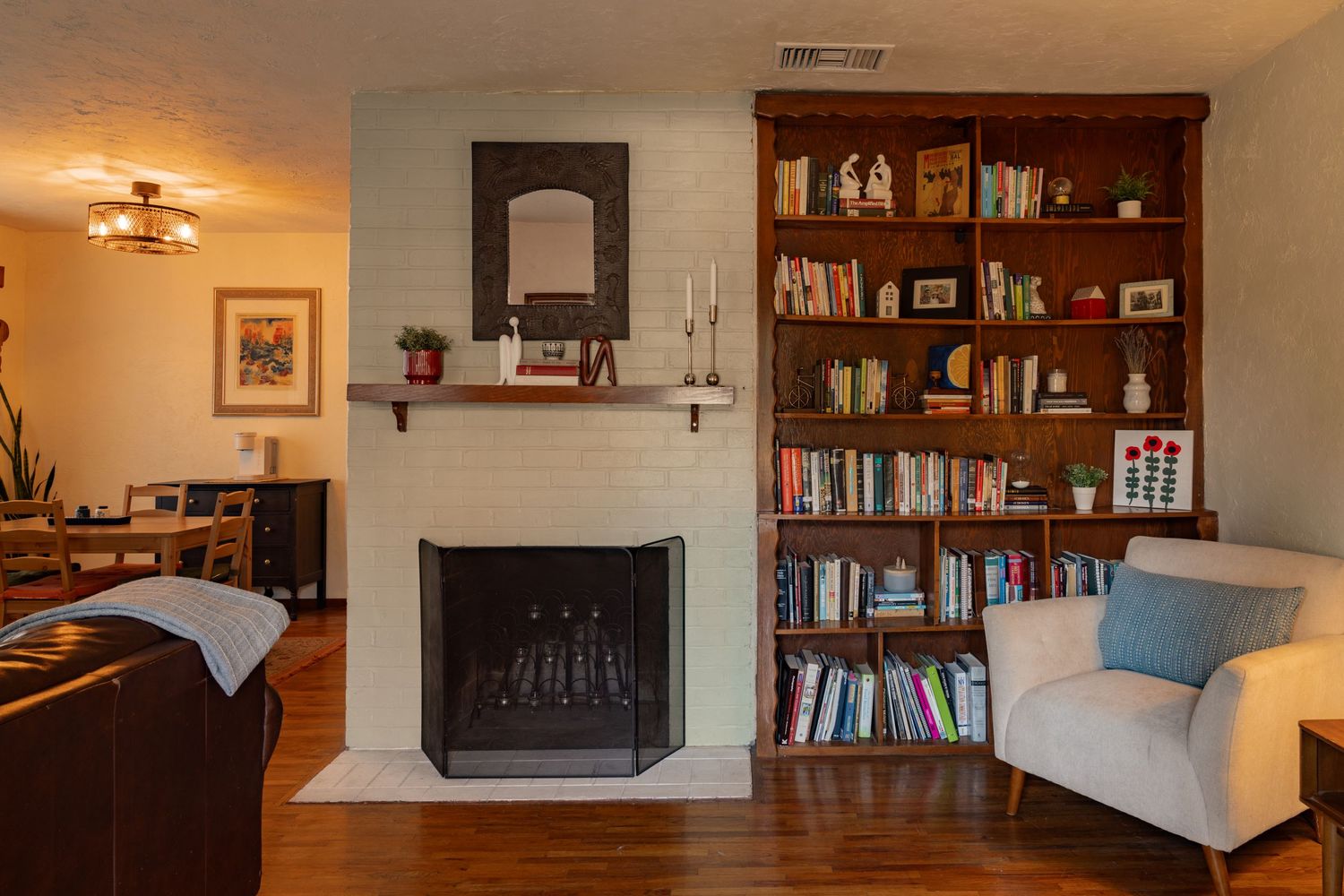 Panoramic view of a cozy living room interior with built-in bookshelves and a fireplace in warm lighting.