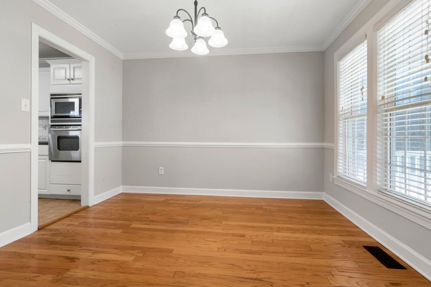 Modern home interior featuring hardwood floors, white walls, and large windows with natural lighting throughout the space.