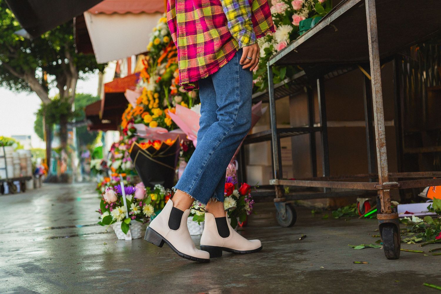 Feet of people wearing colorful sneakers and jeans standing in a row at an outdoor event.