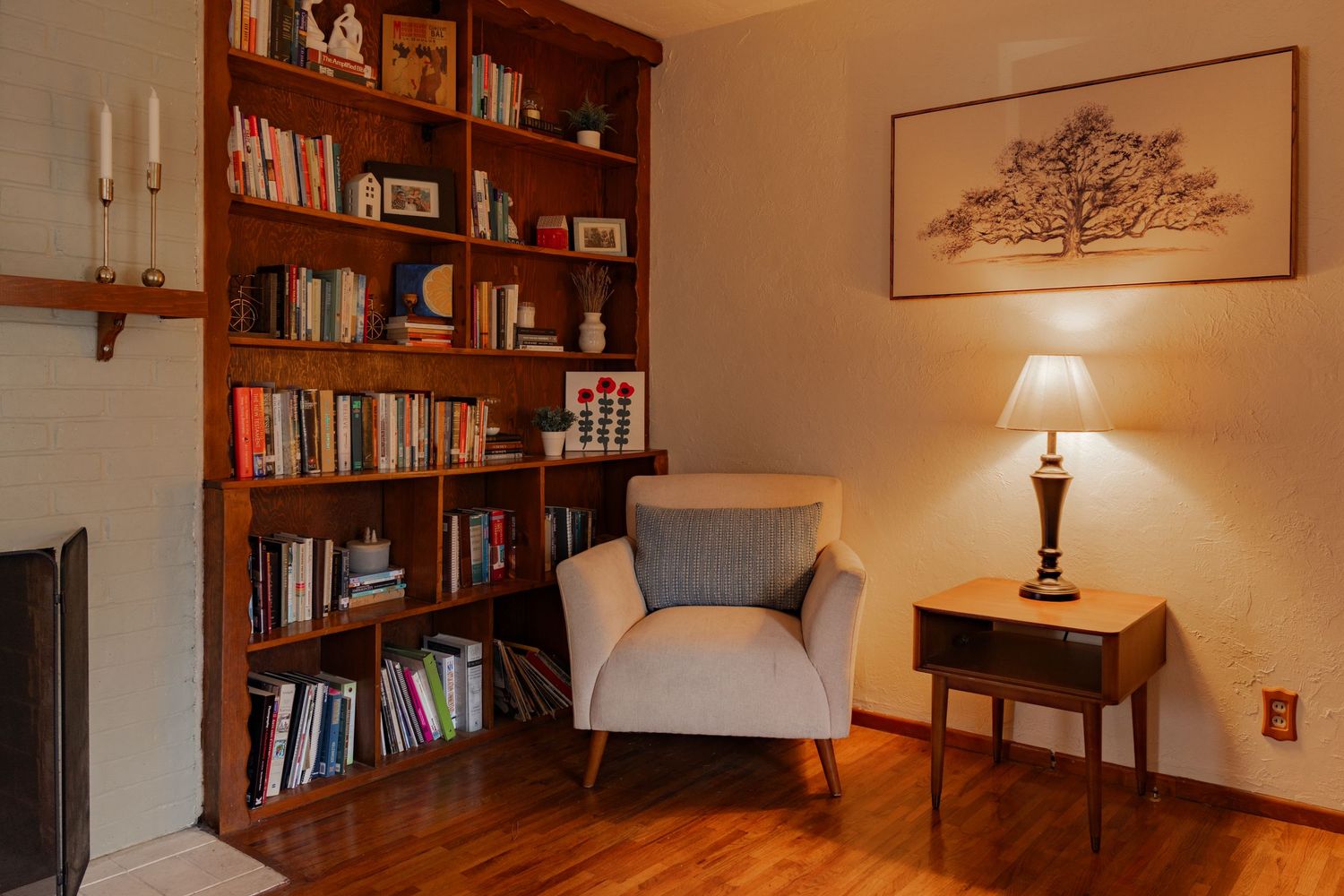 Cozy home library with wooden bookshelves, table lamp, and comfortable seating in warm lighting.