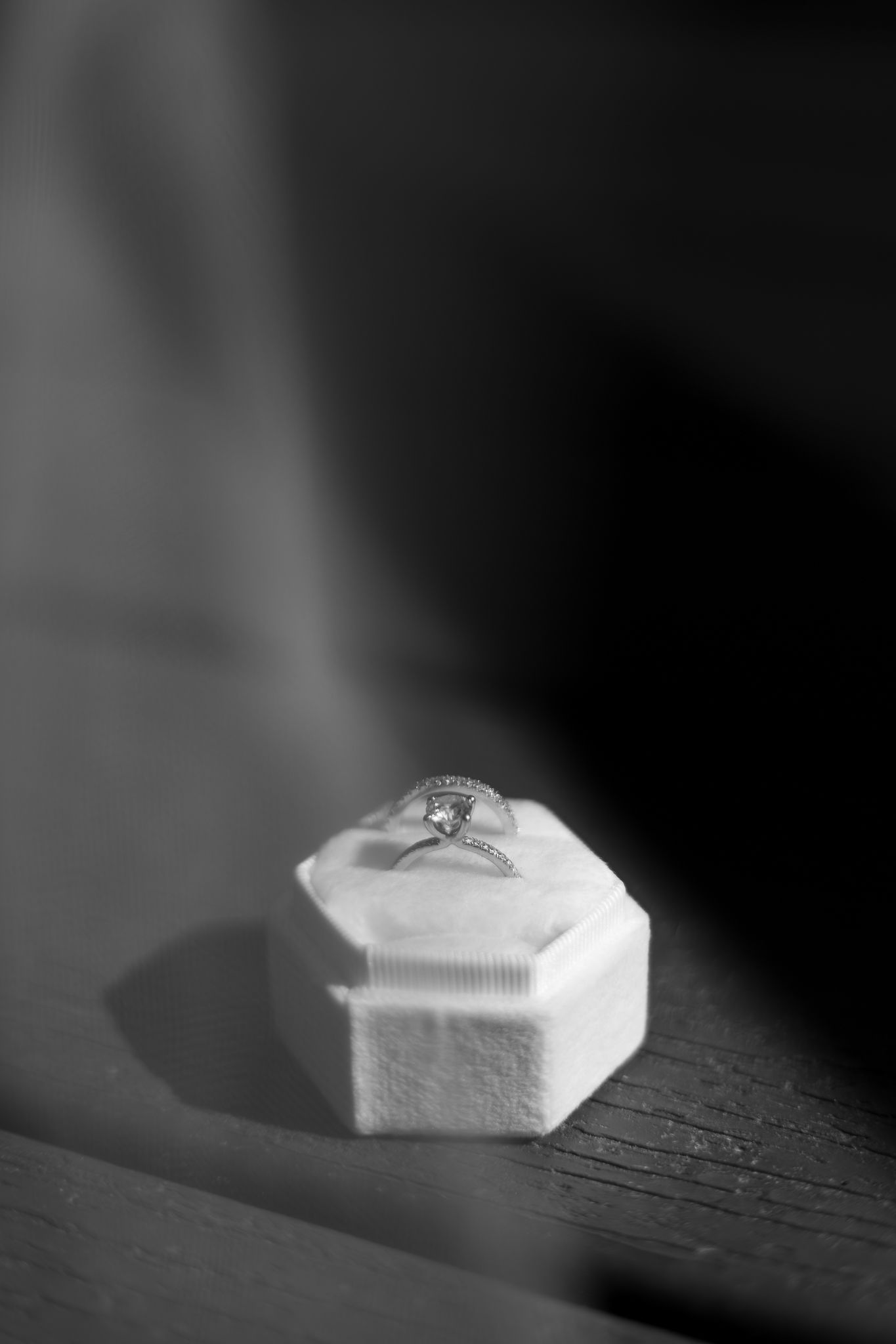 A white hexagonal nut sits in dramatic lighting on a dark wooden surface creating stark contrast and shadows.