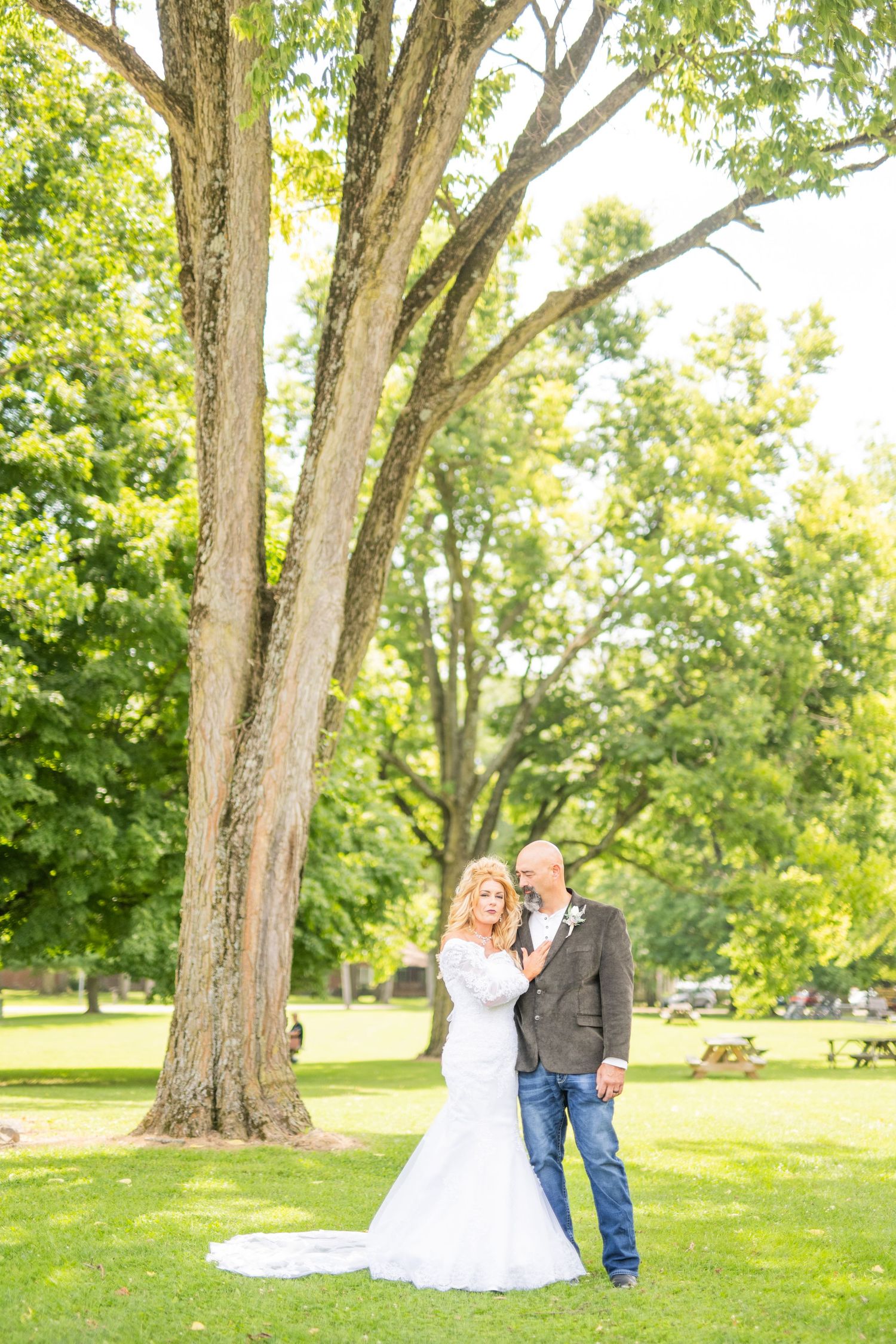 Wedding photography session in a park with mature trees providing natural backdrop.