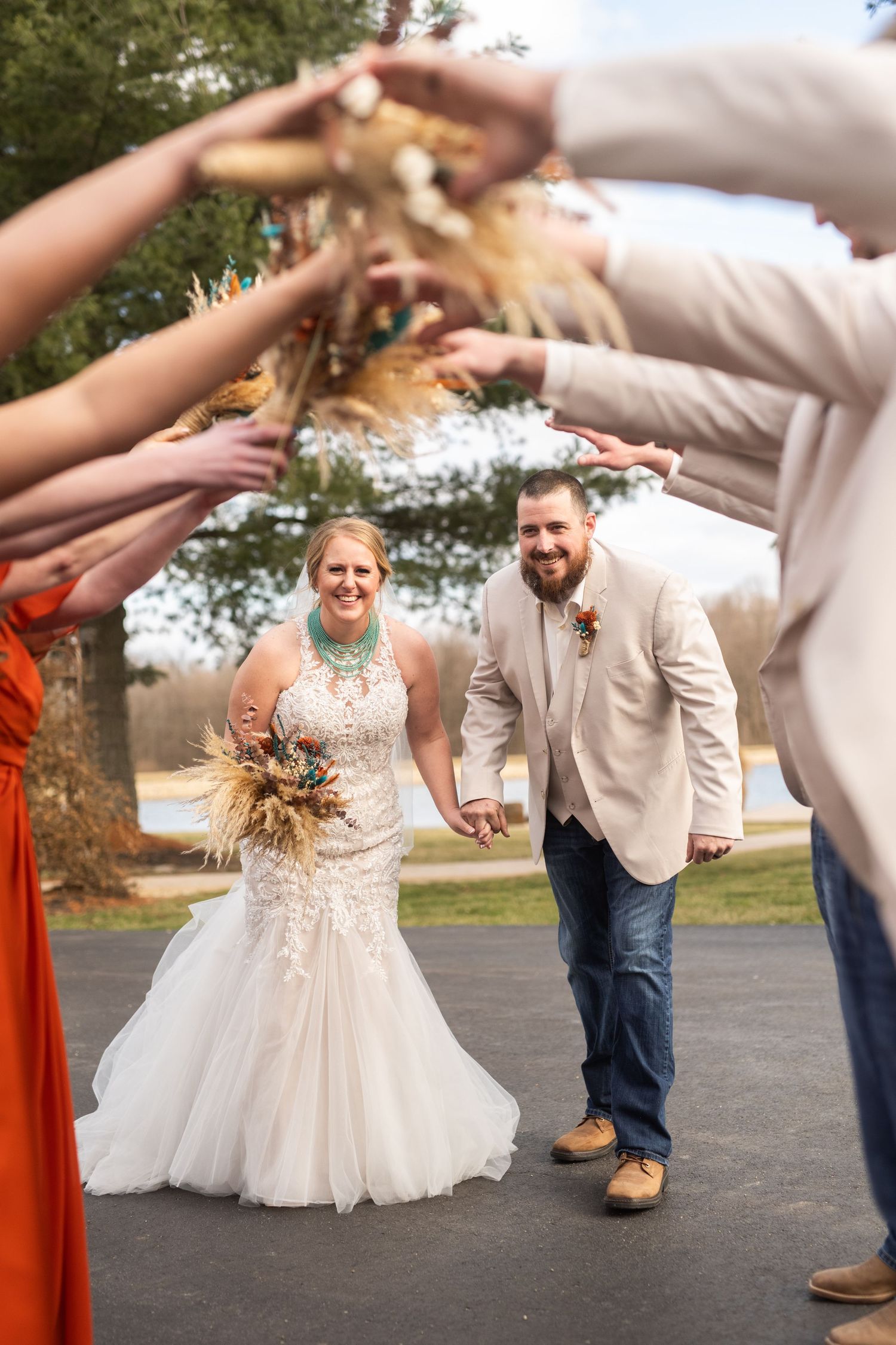 Wedding party forms celebratory arch tunnel outdoors.