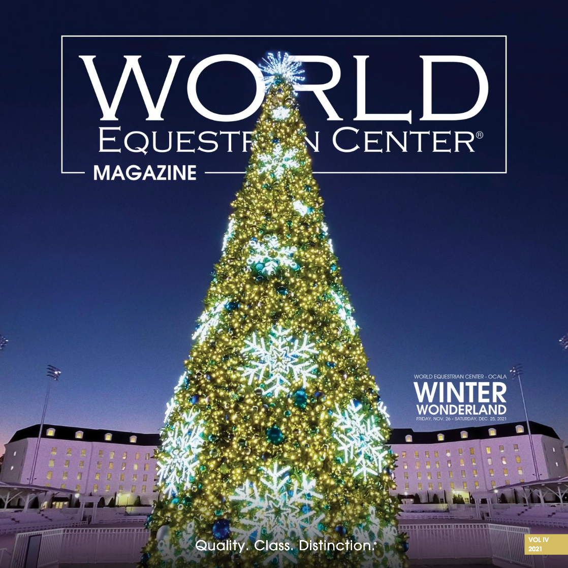 Illuminated Christmas tree glows against twilight sky at World Equestrian Center with decorative lights and signage.