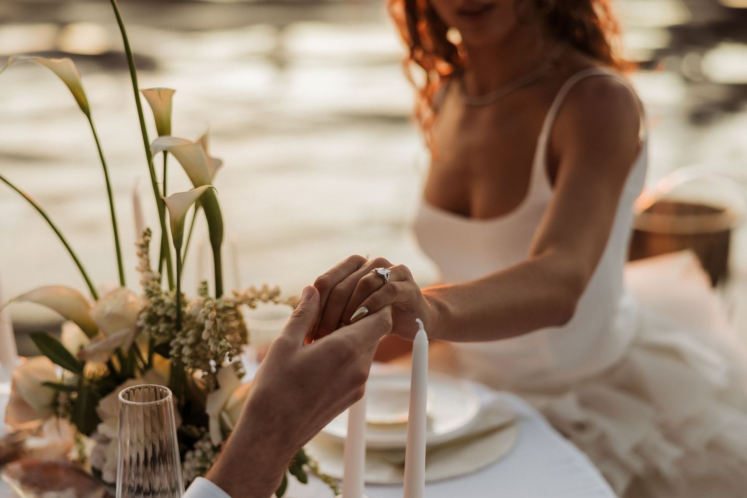 Elegant table setting with candles and flowers at an intimate oceanside wedding reception.
