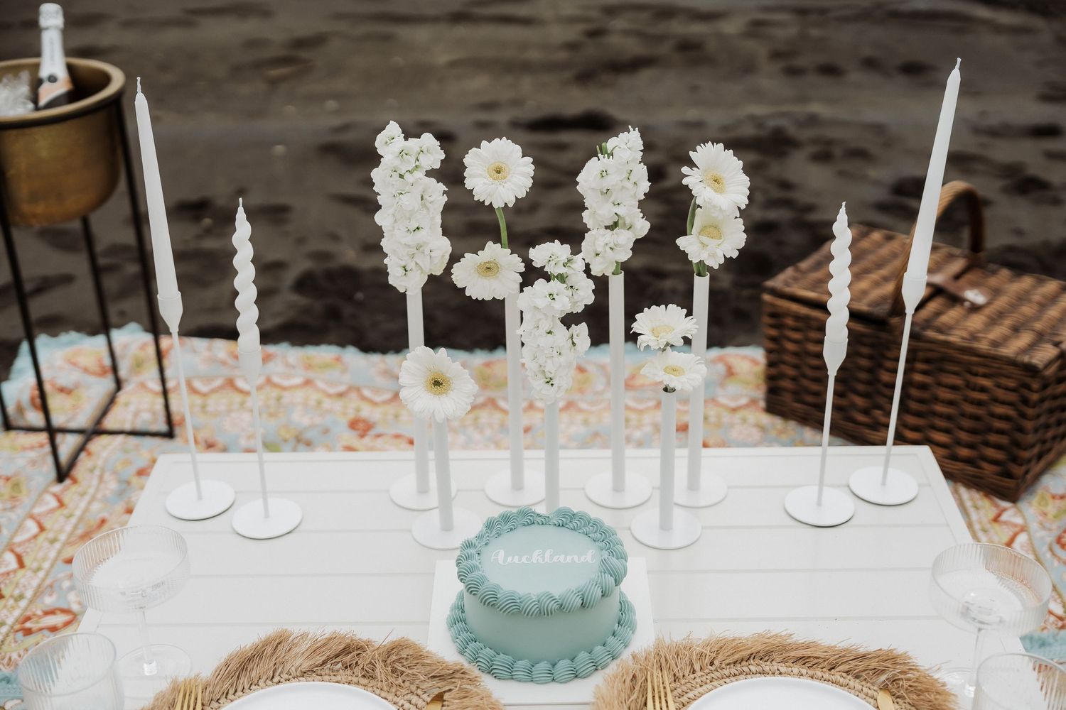 Elegant table setting with white candles and light blue accents for an outdoor celebration.