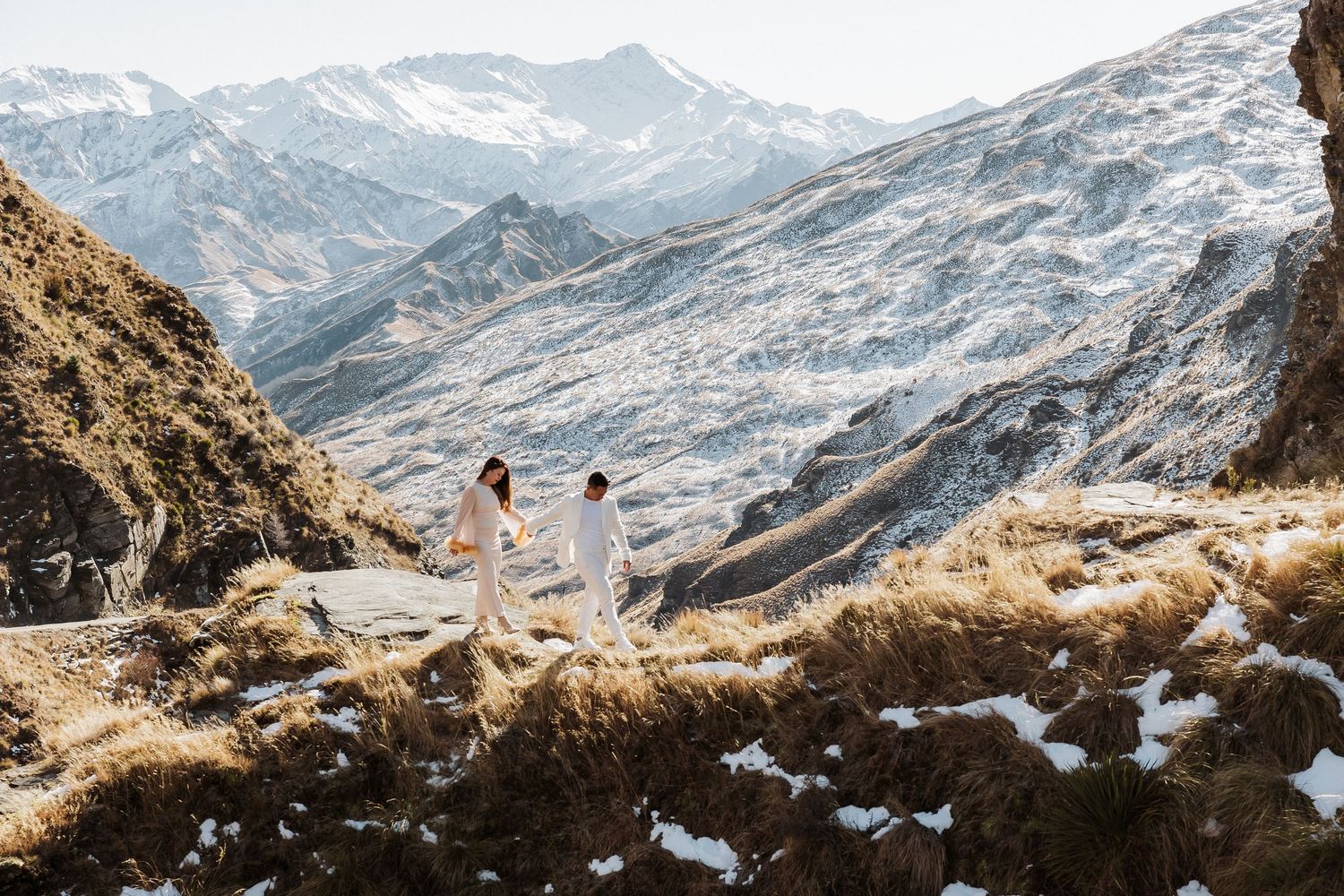 Majestic mountain range with snow-covered peaks rising above brown winter terrain.