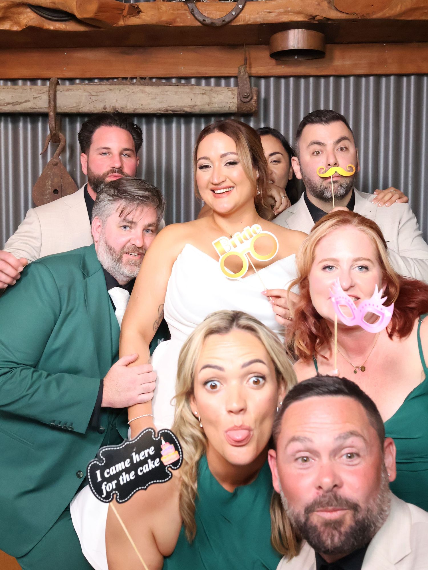 A group poses together in a photo booth with fun props and silly expressions making memorable moments at a celebration.