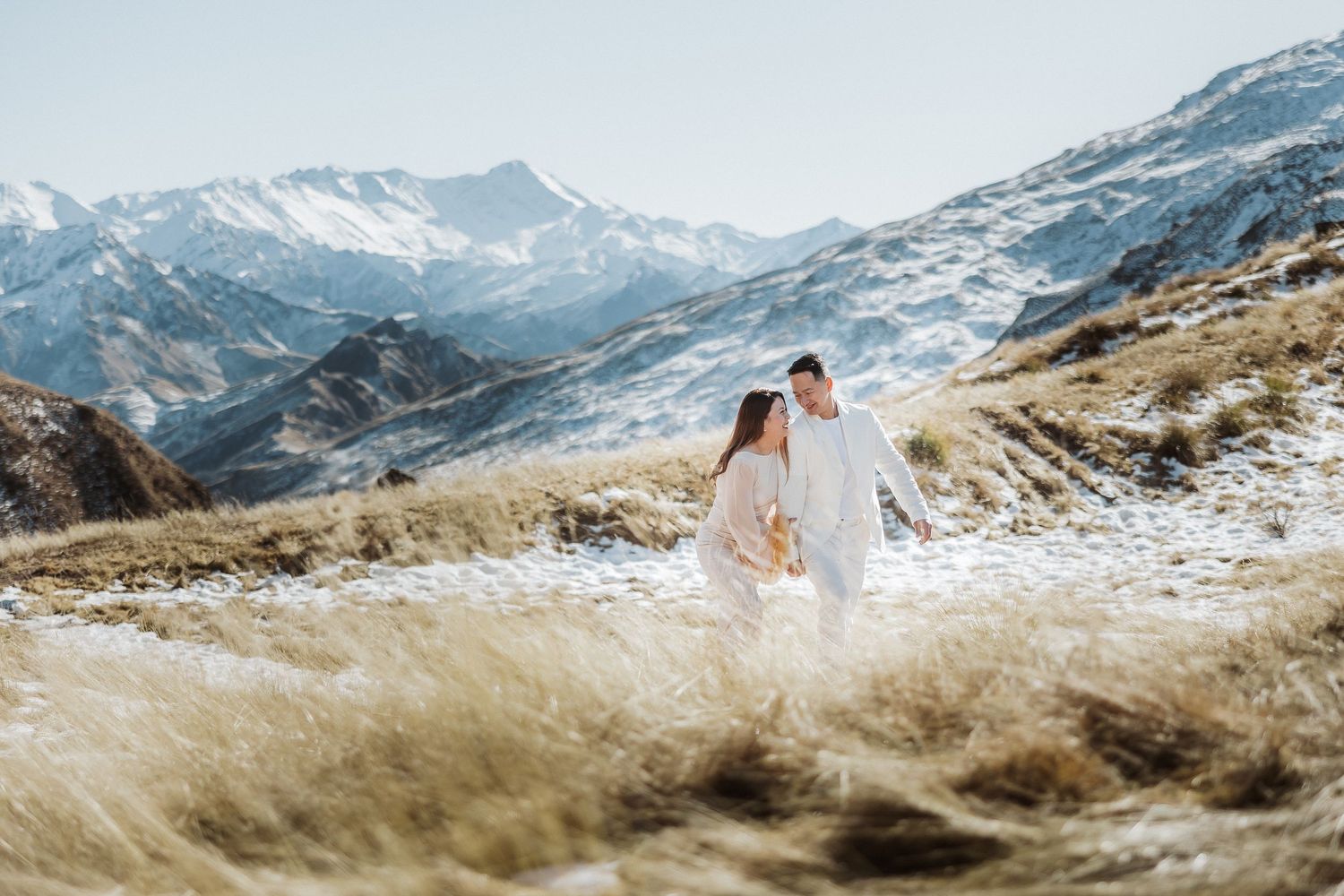 Dramatic mountain landscape with snow-dusted peaks and golden grass slopes in winter.