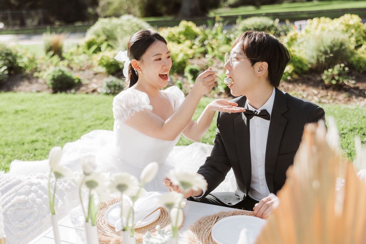 Couple enjoying champagne and laughter during an elegant outdoor picnic celebration.
