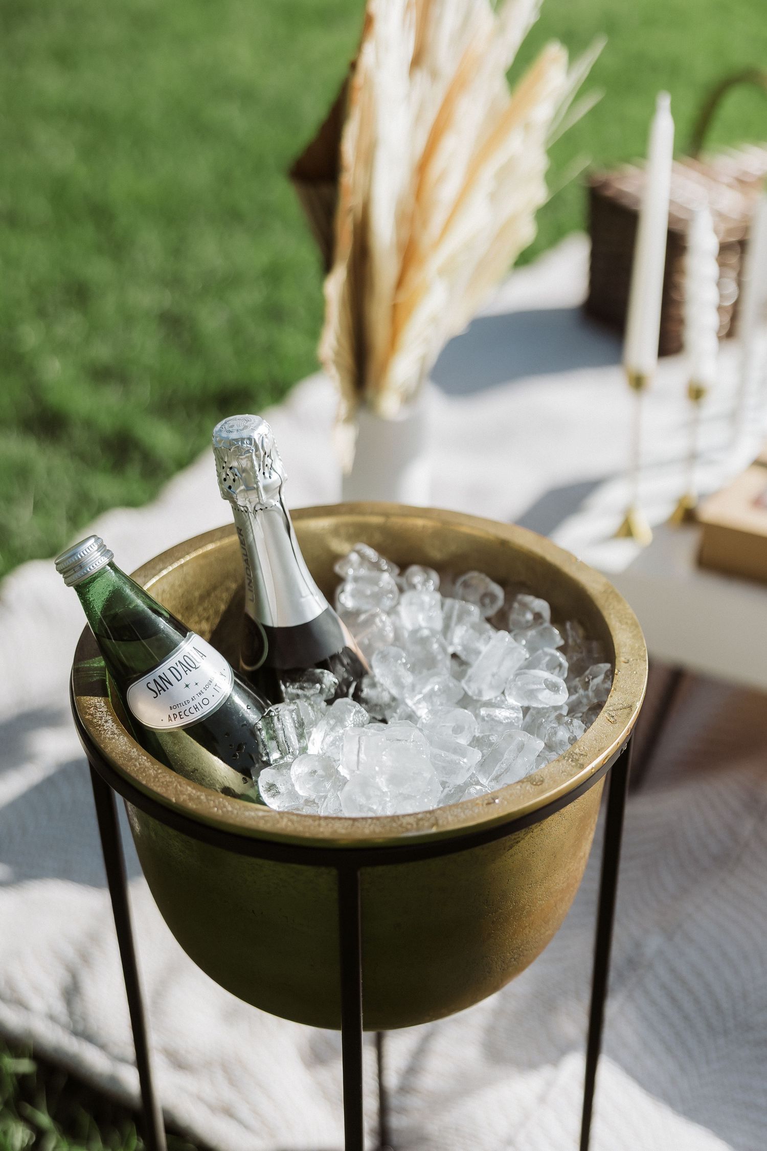 Champagne bottles chilling in rustic wooden bowls filled with ice at an outdoor event setup.