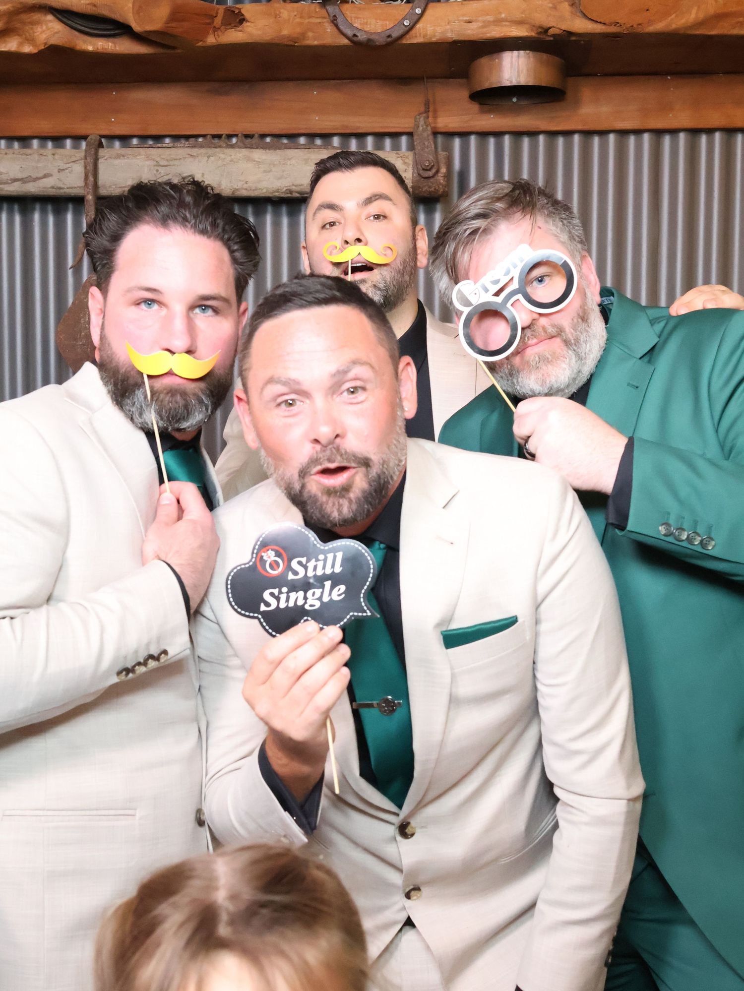A group of people in formal attire pose together making silly faces and gestures in a photo booth sequence.