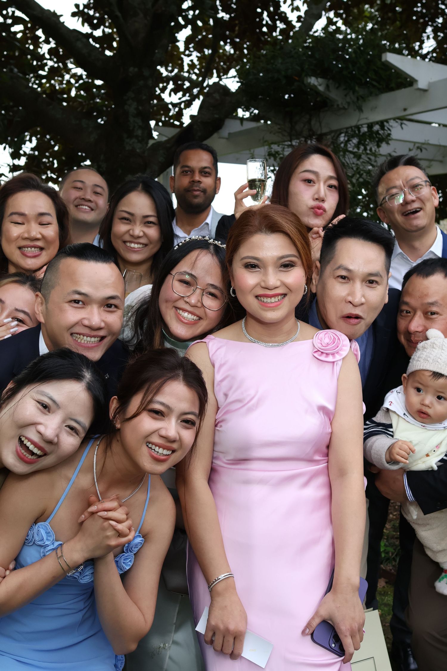 A group of people smile and pose together in a casual outdoor setting wearing pink and blue outfits.