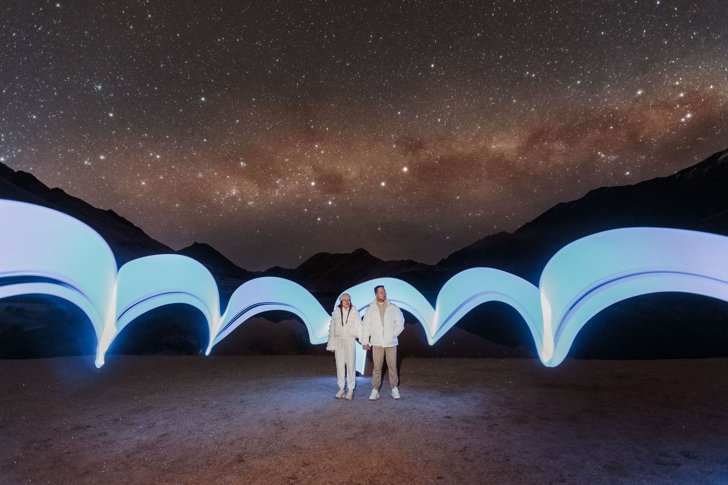 A stunning series of aurora borealis lights dancing across a starry night sky over mountain silhouettes.