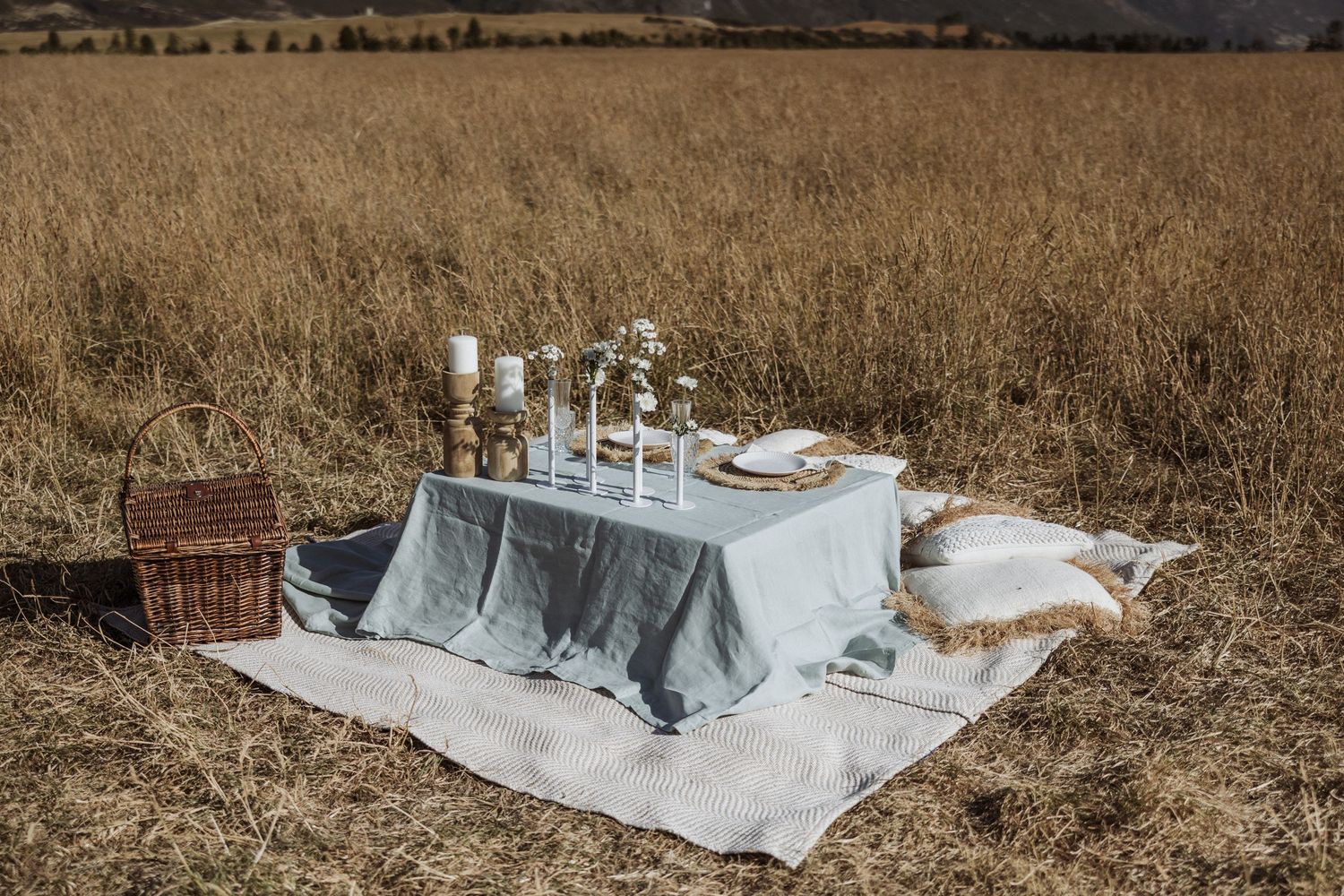 A series of white and blue bedding sets arranged in a row on dry grass in an outdoor setting.