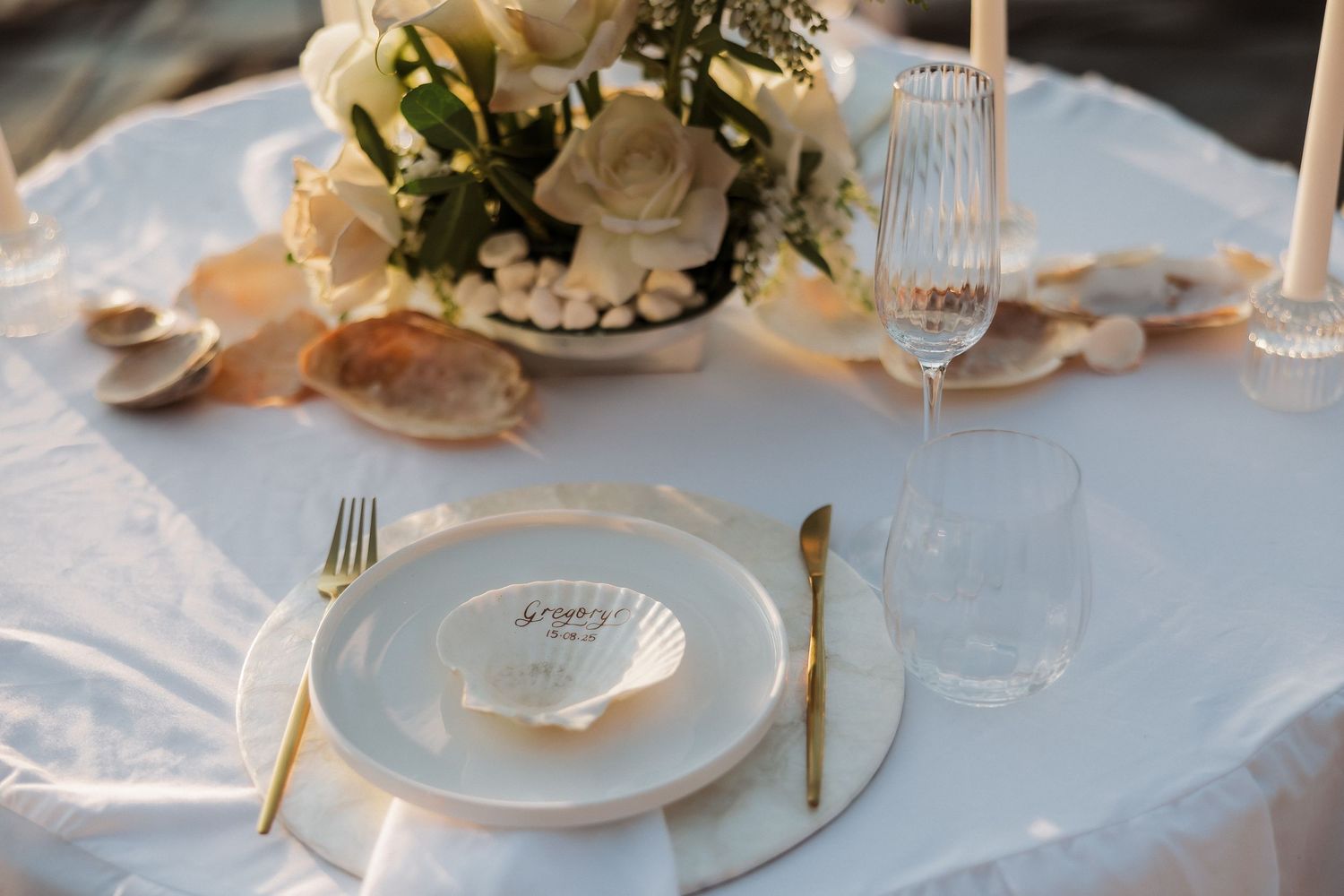 Elegant wedding reception table settings with white linens, gold accents, and delicate floral centerpieces.