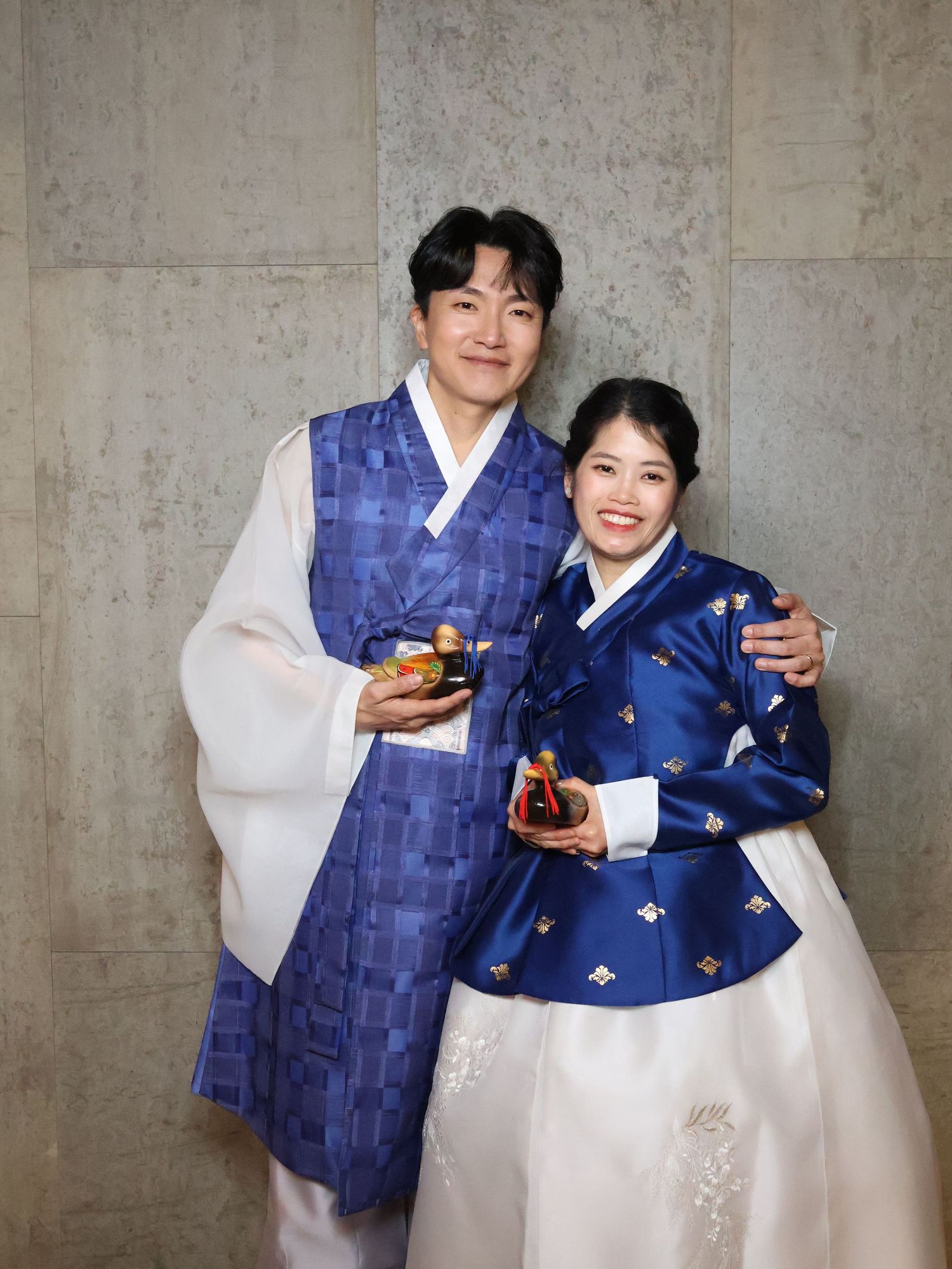 People wearing traditional Korean hanbok outfits in blue and white pose together in a series of celebratory photos.