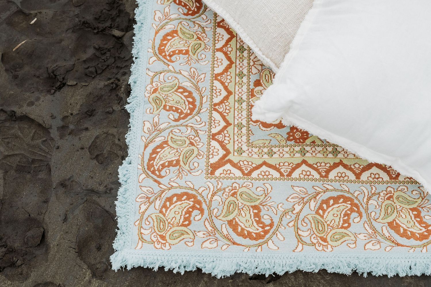 Decorative white napkin with orange paisley pattern details on a dark surface.