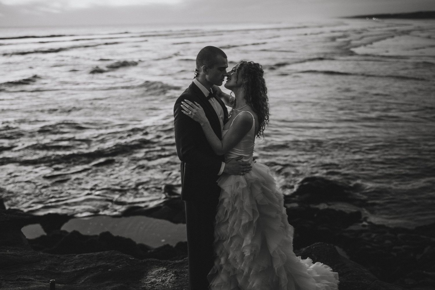 A romantic beach wedding photoshoot silhouette series at sunset shows intimate moments between the couple by the ocean.
