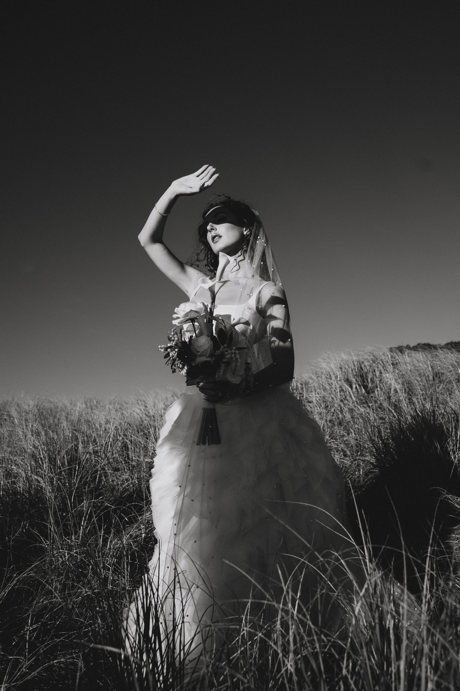 A black and white photo sequence shows a figure emerging and spinning through tall grass in an artistic dance performance.