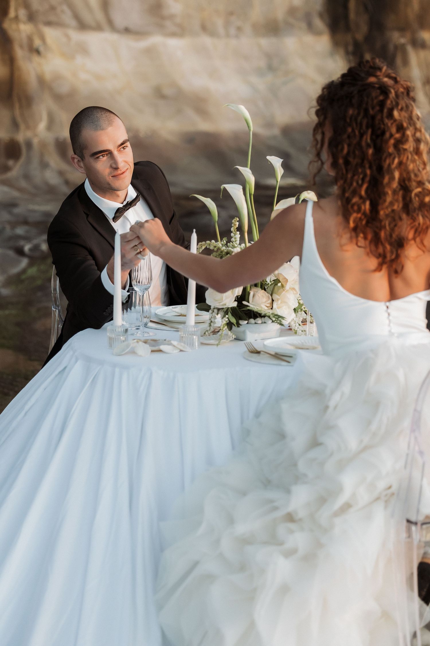 Elegant table setting at a wedding reception with white linens and floral centerpieces.