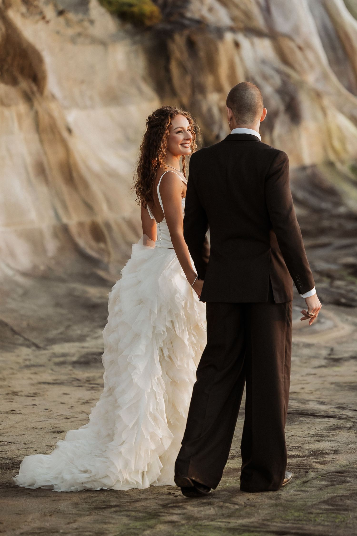 Romantic beach wedding photos showing couple walking together on sandy shore at sunset.