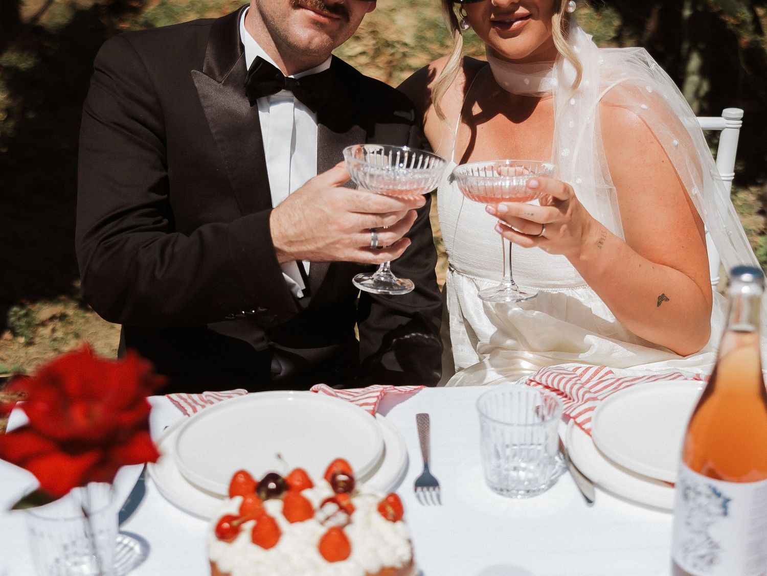 Elegant table settings at an outdoor reception with glassware and dessert plates.