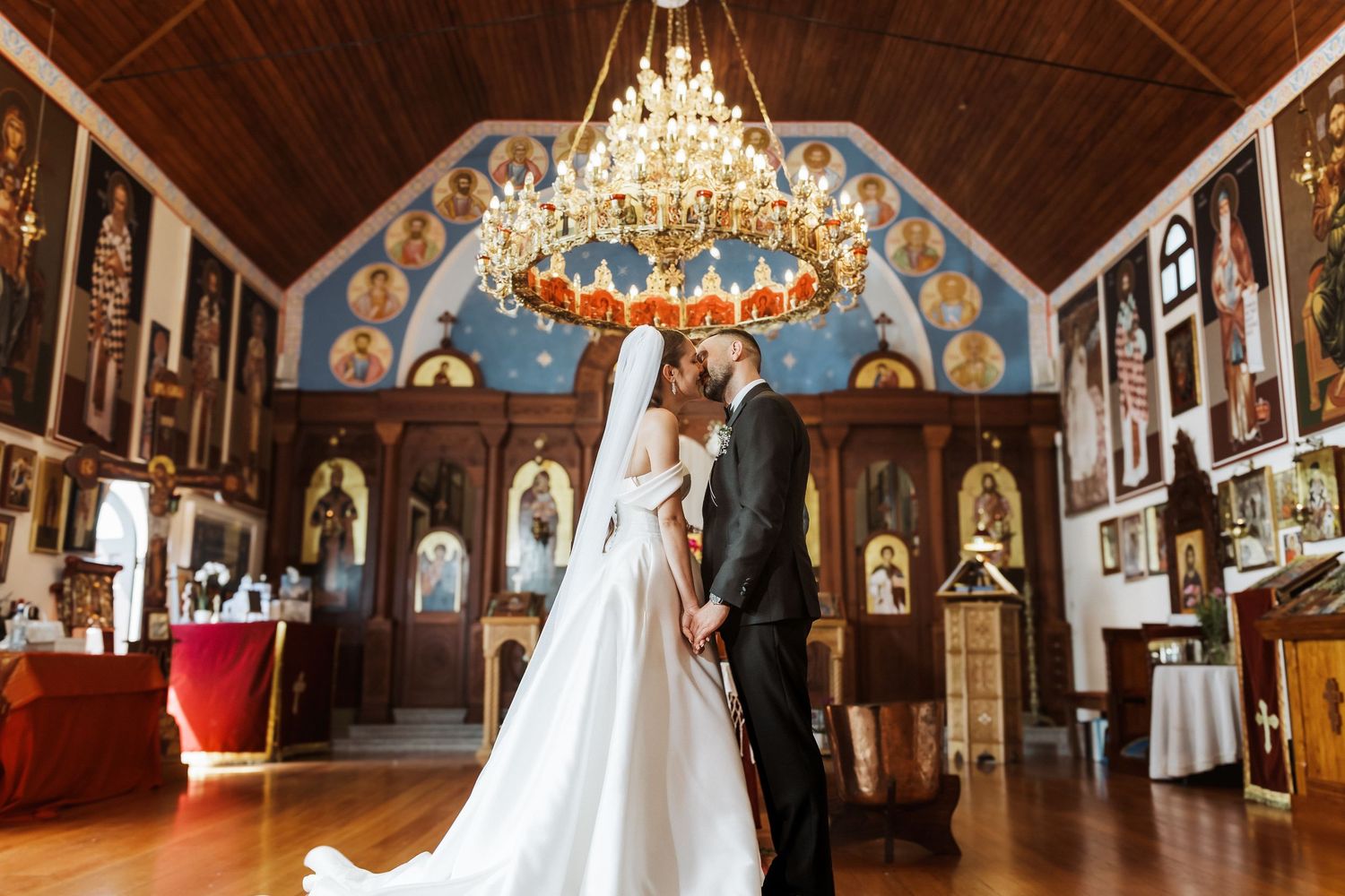 A panoramic view of an ornate church interior with chandeliers, religious artwork, and vaulted wooden ceilings.