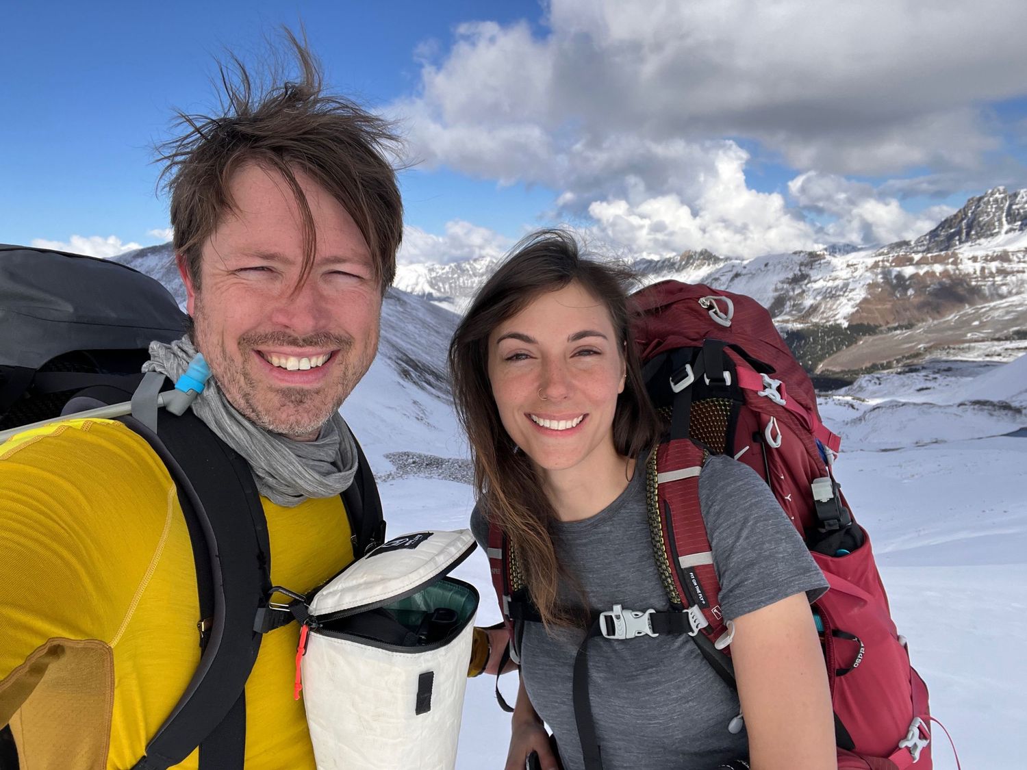 Evan Will and Kristen Lusk winter hiking in a snowy mountain landscape with cloudy sky backdrop in Jasper National Park in the Rockies