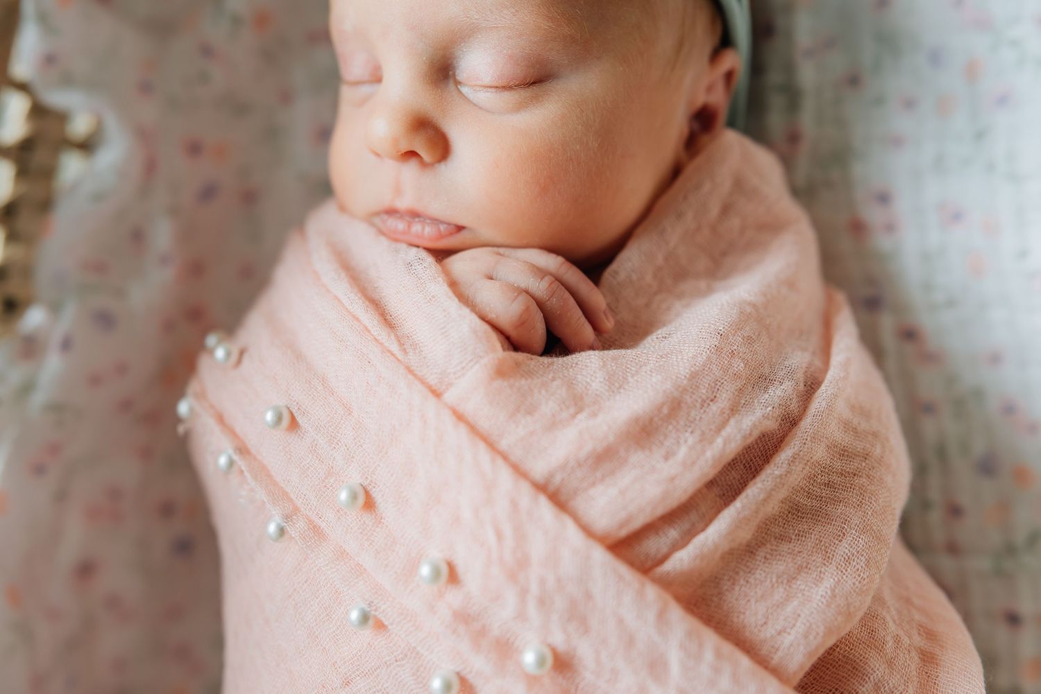 Tiny fingers of newborn baby popping our of a swaddle wrap in natural light photo.