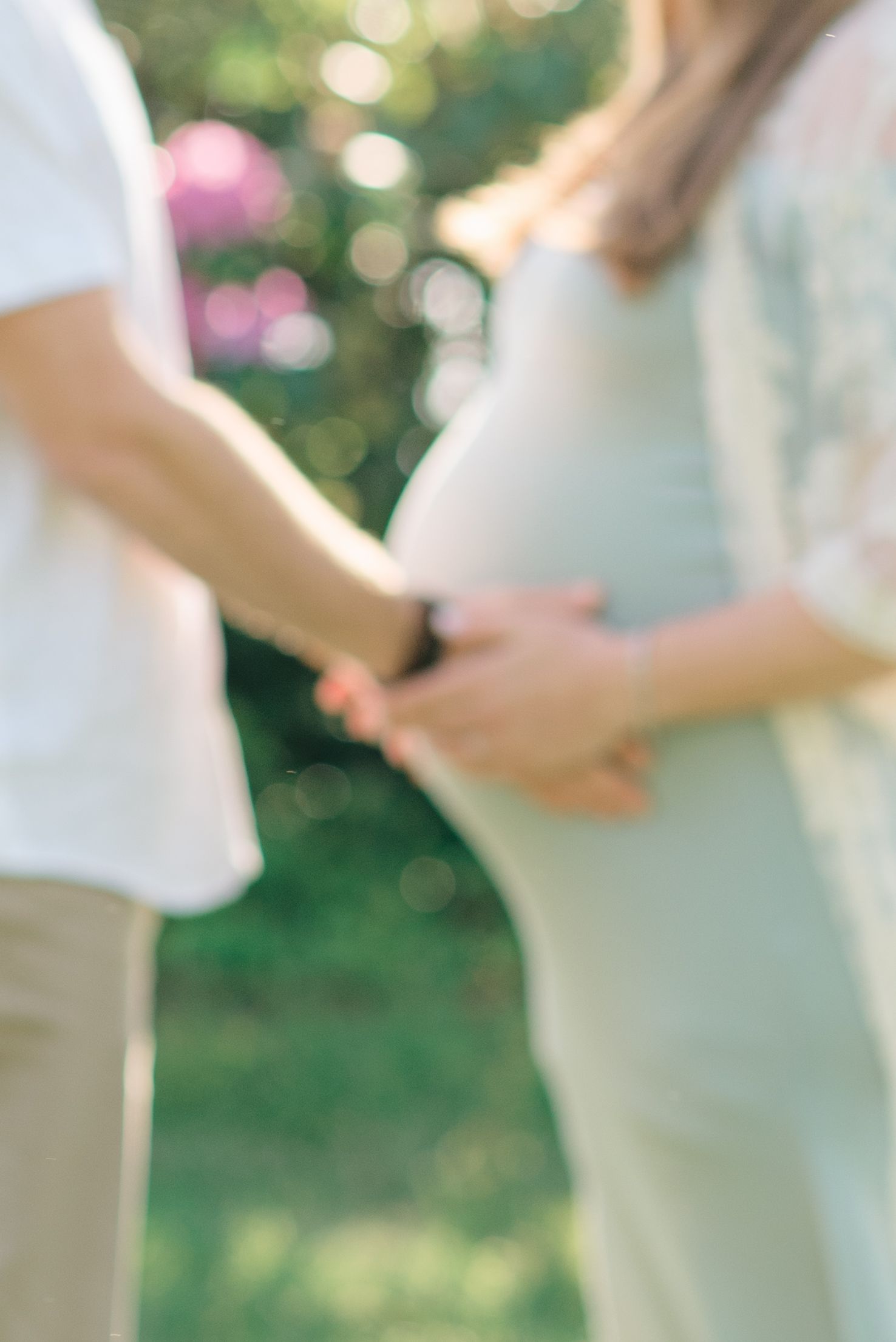 A close up of a pregnant woman's belly being held by her husband's hands.