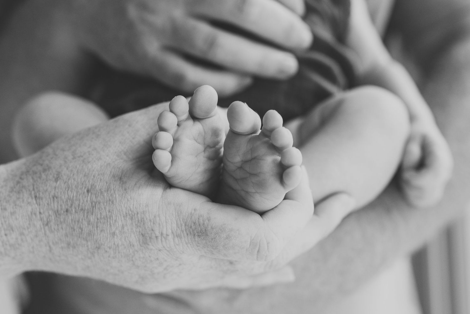 Close-up of baby toes in mother and father's hands during newborn shoot in Point Pleasant, NJ.