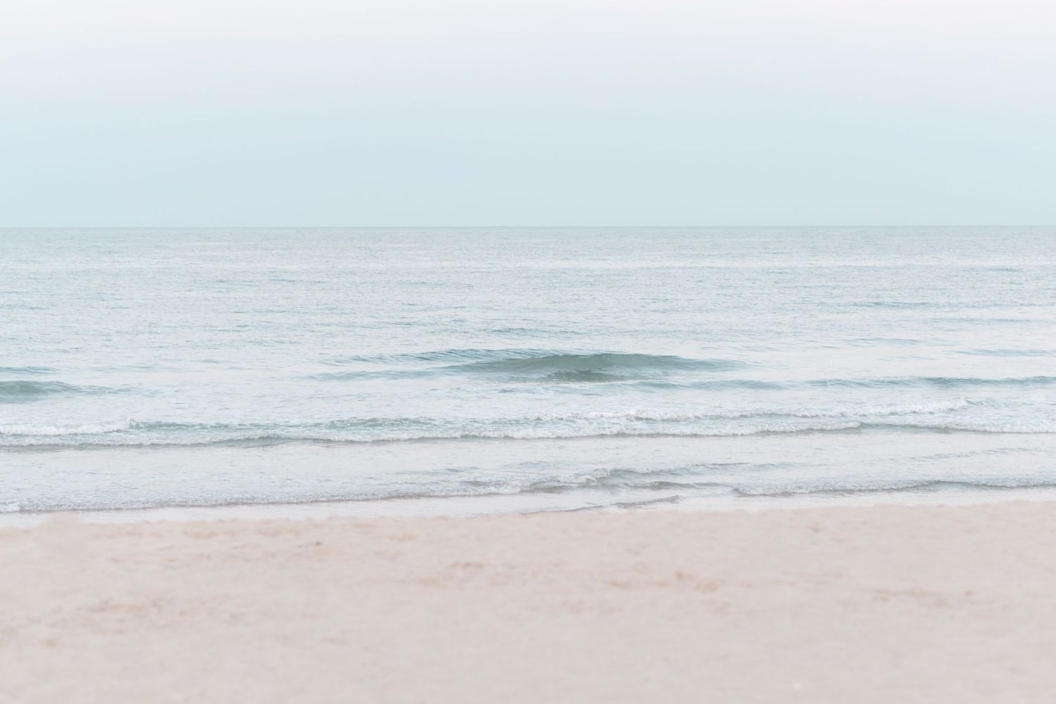 The ocean along a shoreline of sandy beach.