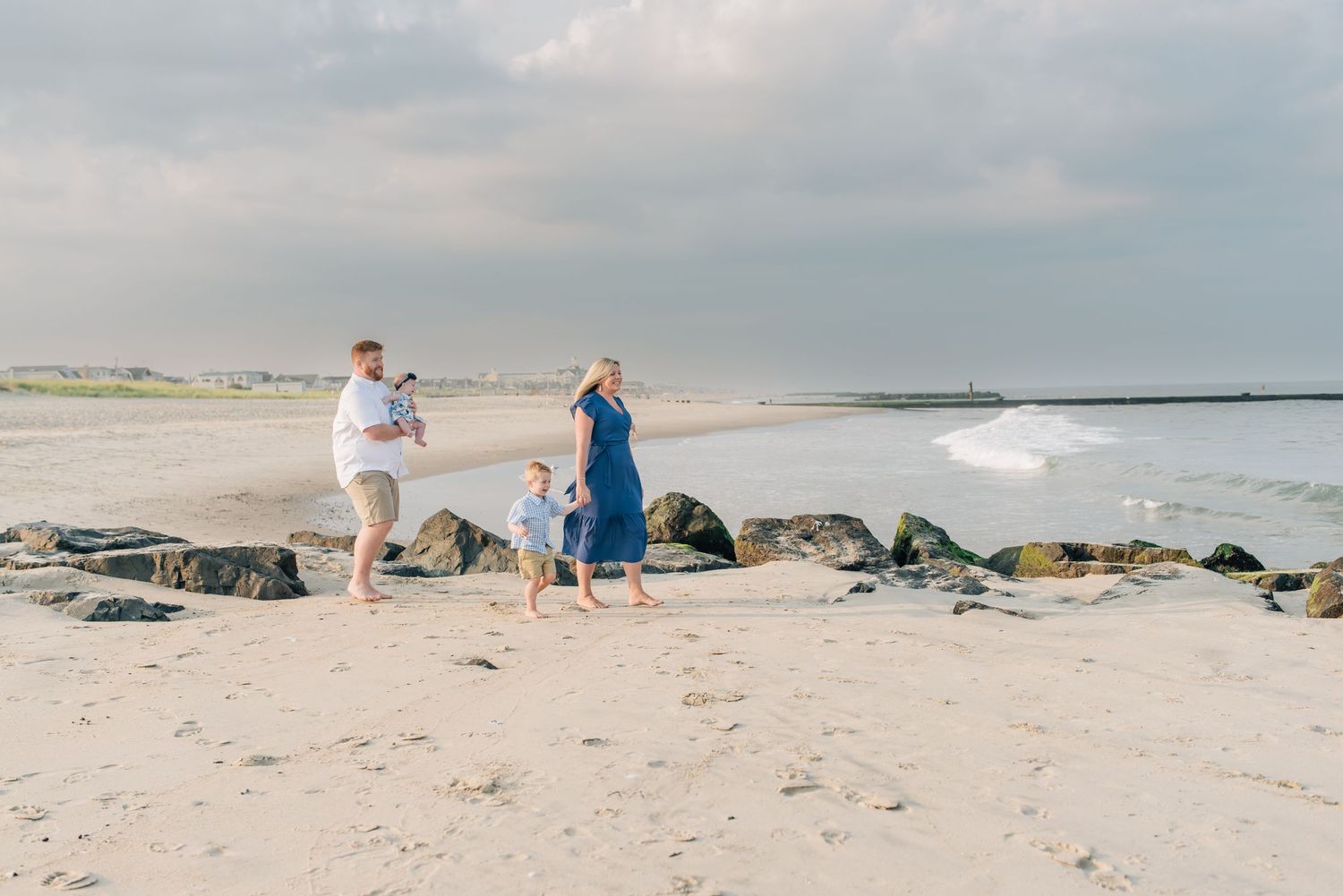 A family of four walks down to the ocean on the beach at Lauren Marie Photography session.