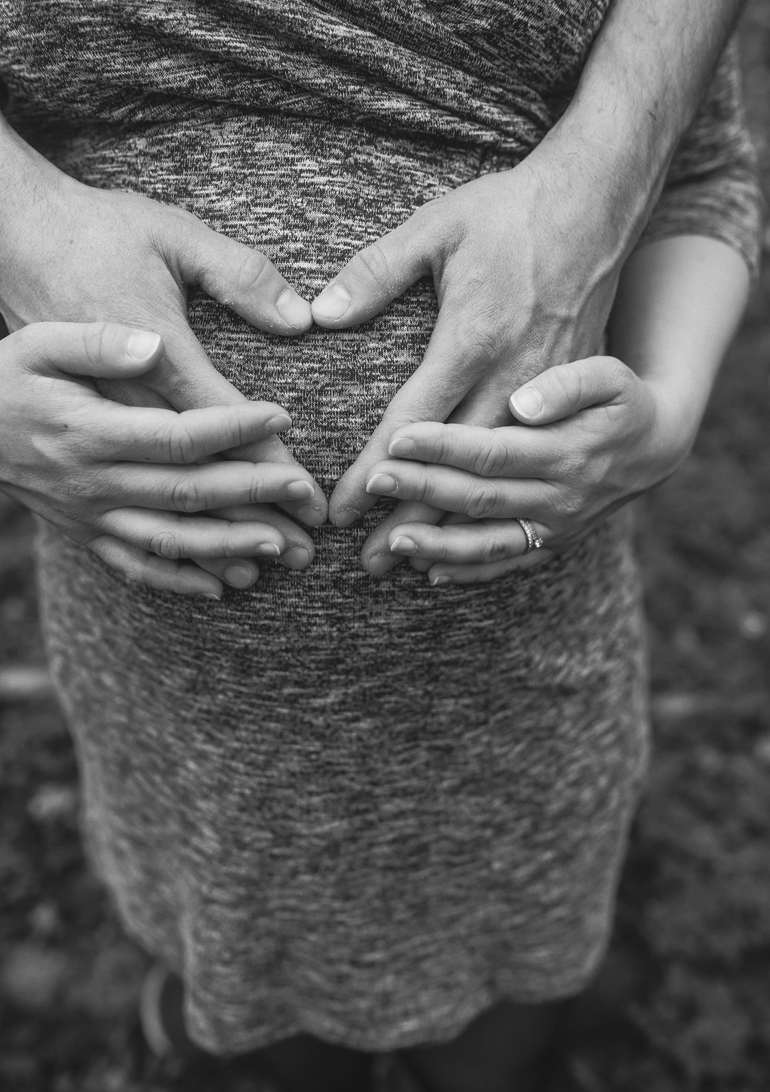 Gravidfotografering med detaljbild av händer över gravidmage